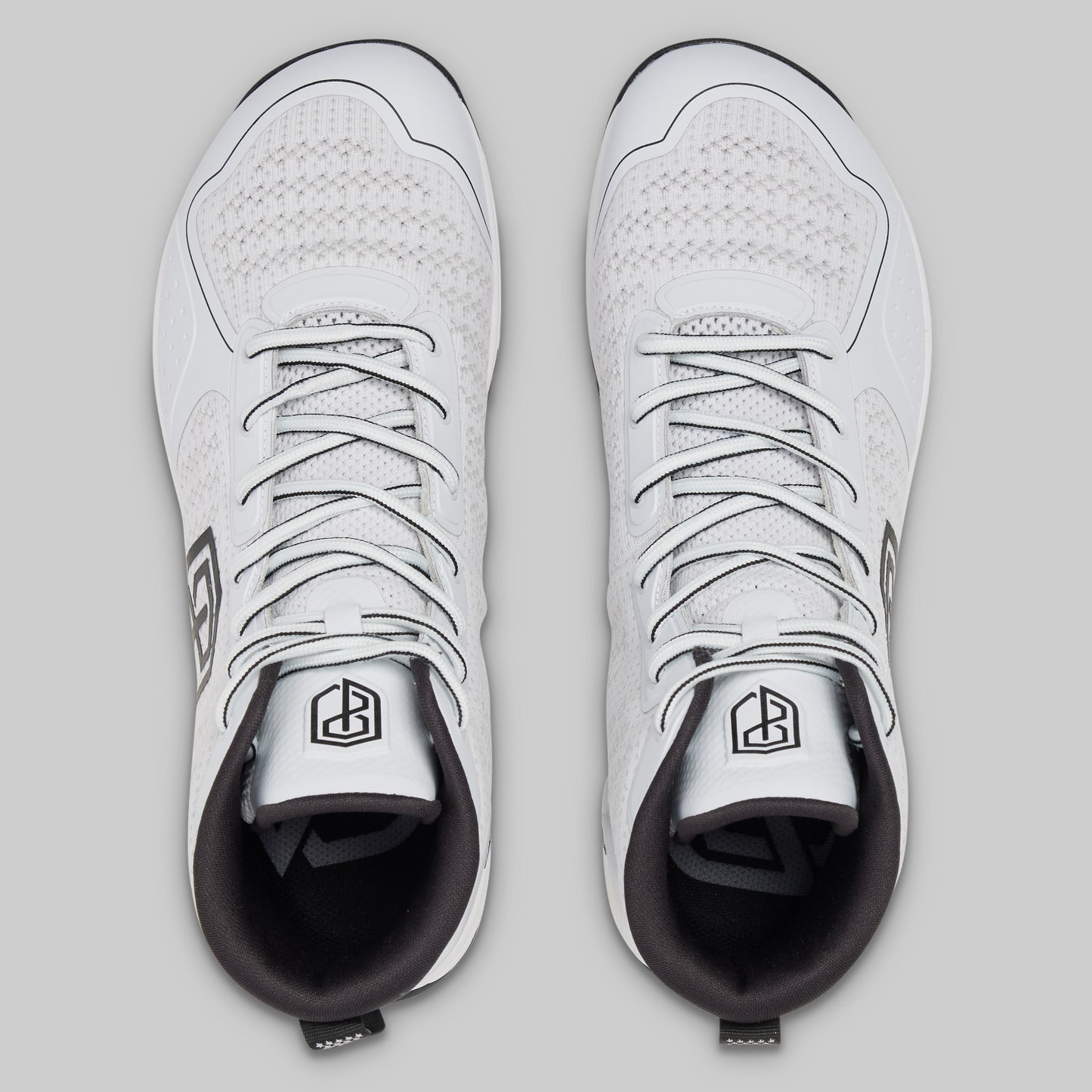 Pair of white sneakers with black soles on a light gray background