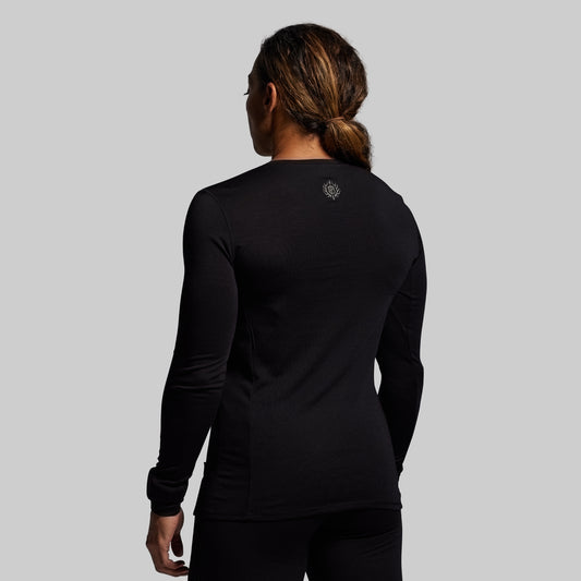 Person wearing a black long-sleeve shirt with a logo on the back against a gray background
