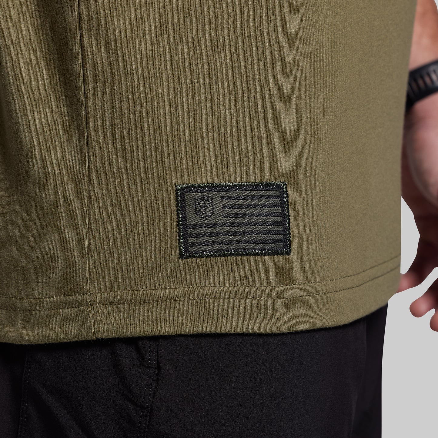 Close-up of a green t-shirt with a patch featuring an American flag design.