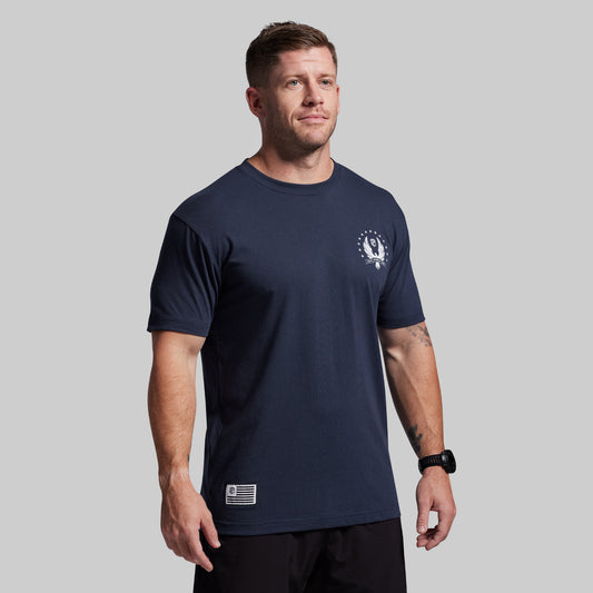 Man wearing a navy blue t-shirt with a logo on a gray background