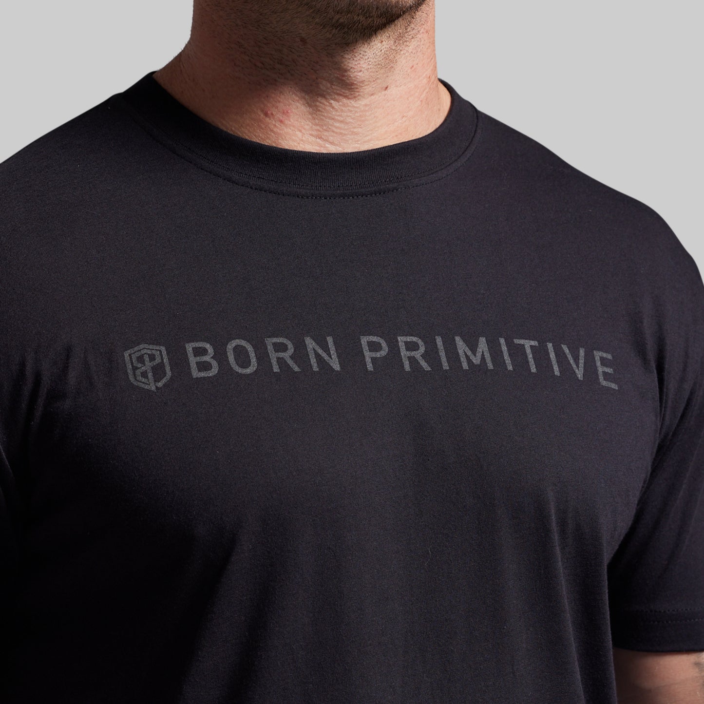 Black t-shirt with 'BORN PRIMITIVE' text on a gray background