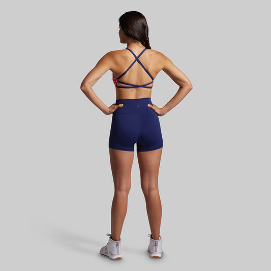 Person wearing a blue sports bra and shorts on a gray background