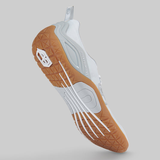 A single athletic shoe shown from a rear three-quarter angle against a solid gray background. The shoe features a white upper with light gray accents and a textured brown outsole.
