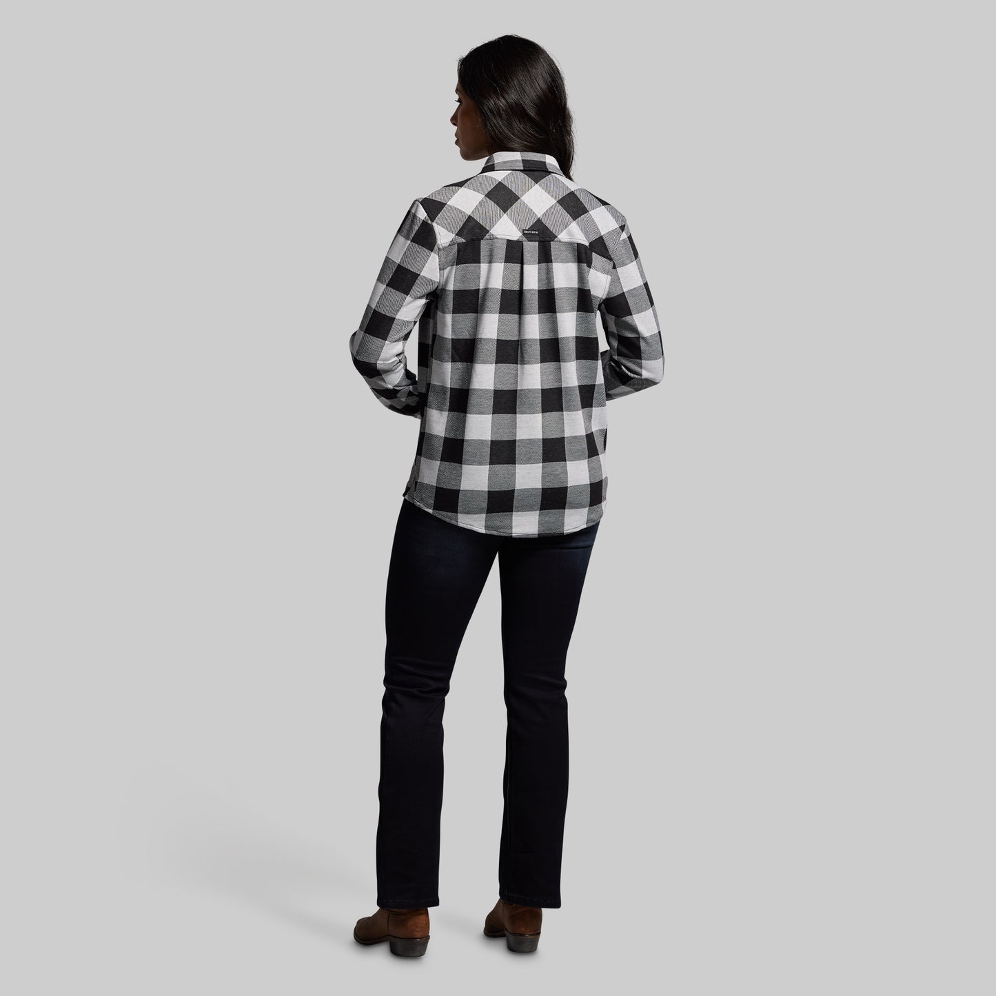 Person wearing a black and white checkered shirt on a gray background