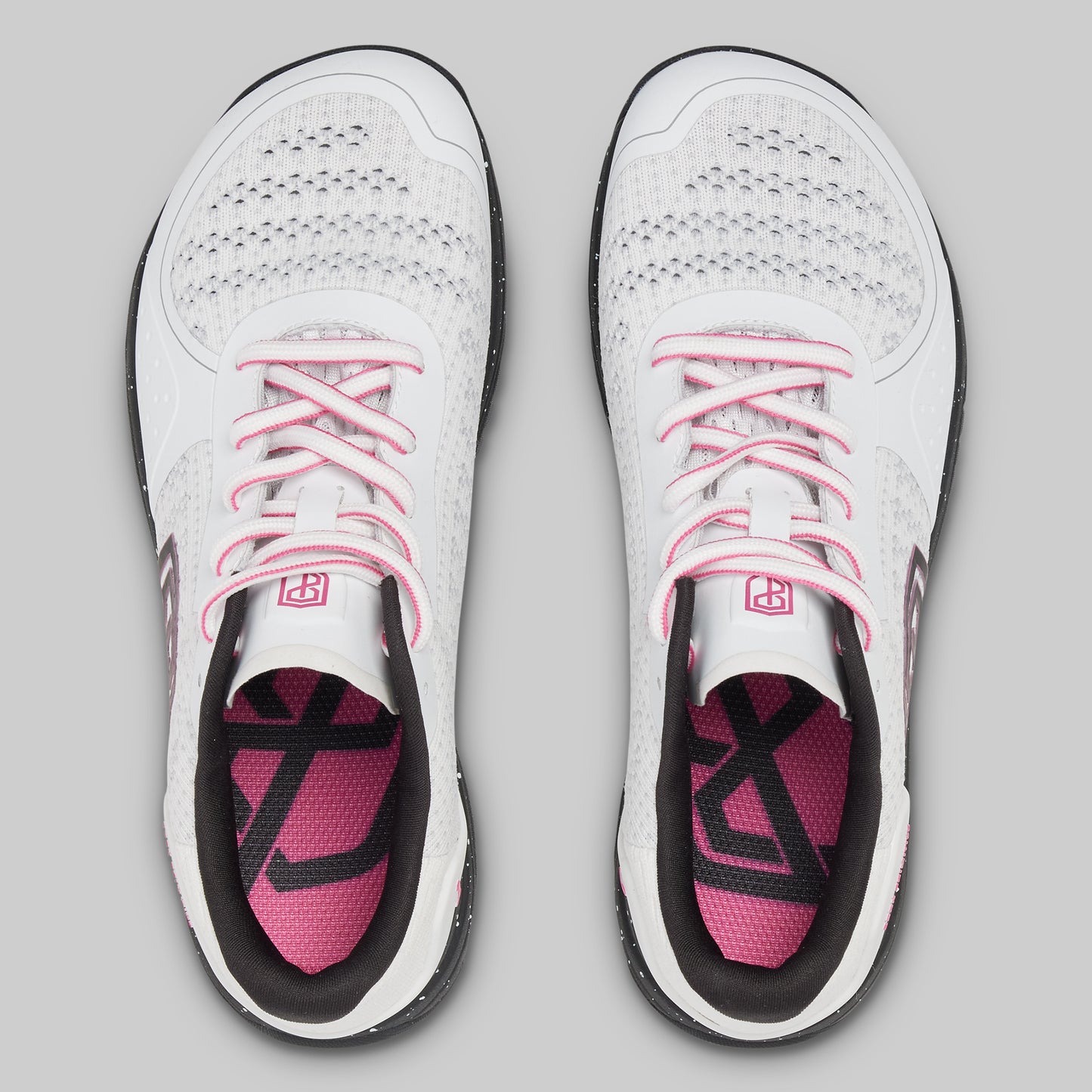 White athletic shoes with pink accents on a gray background