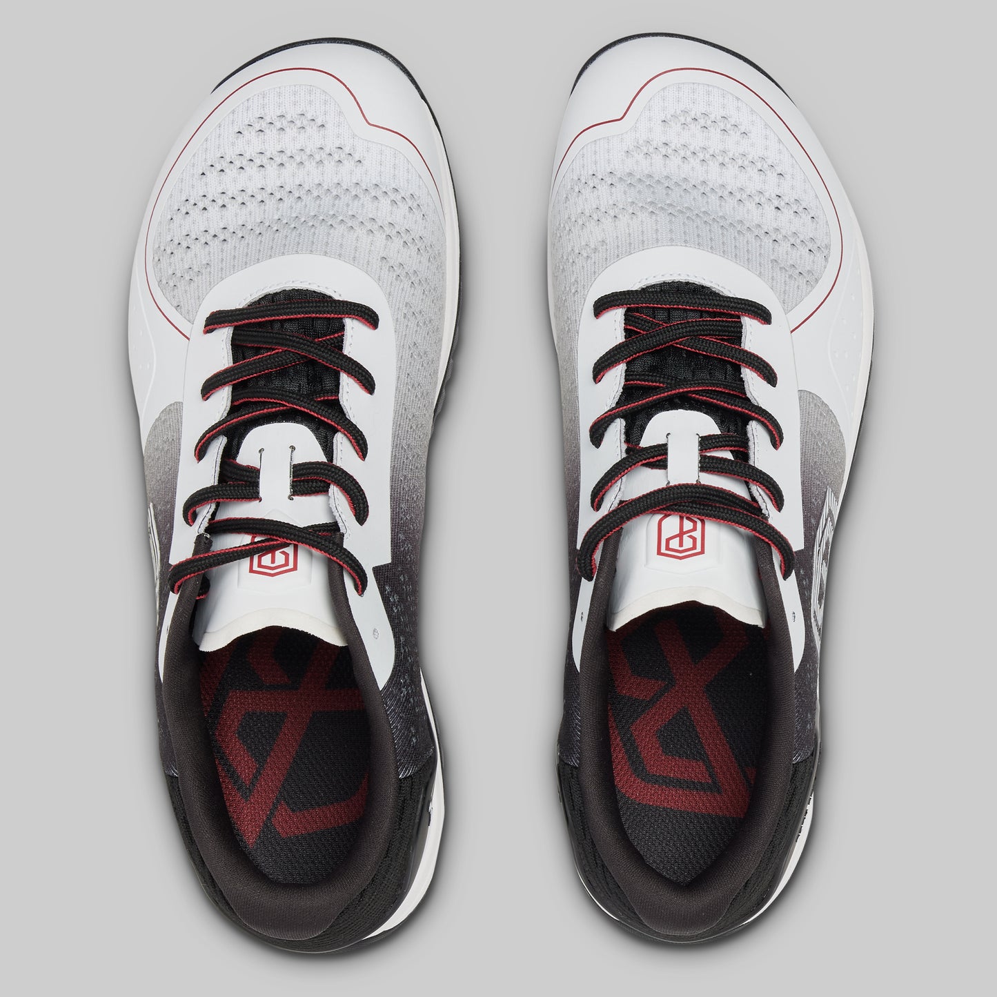 White athletic shoes with black and red accents on a gray background