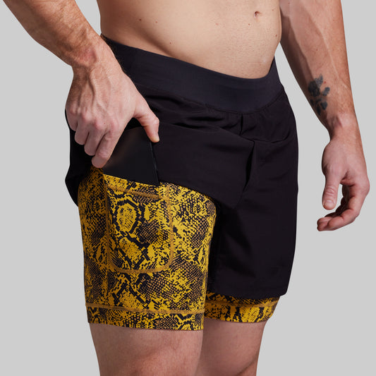 Person wearing black and yellow patterned shorts on a plain background