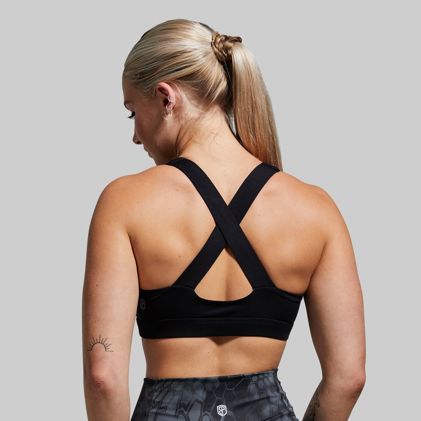 Woman wearing a black sports bra with a gray background