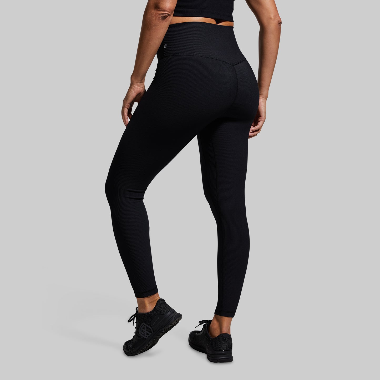 Person wearing black leggings on a gray background