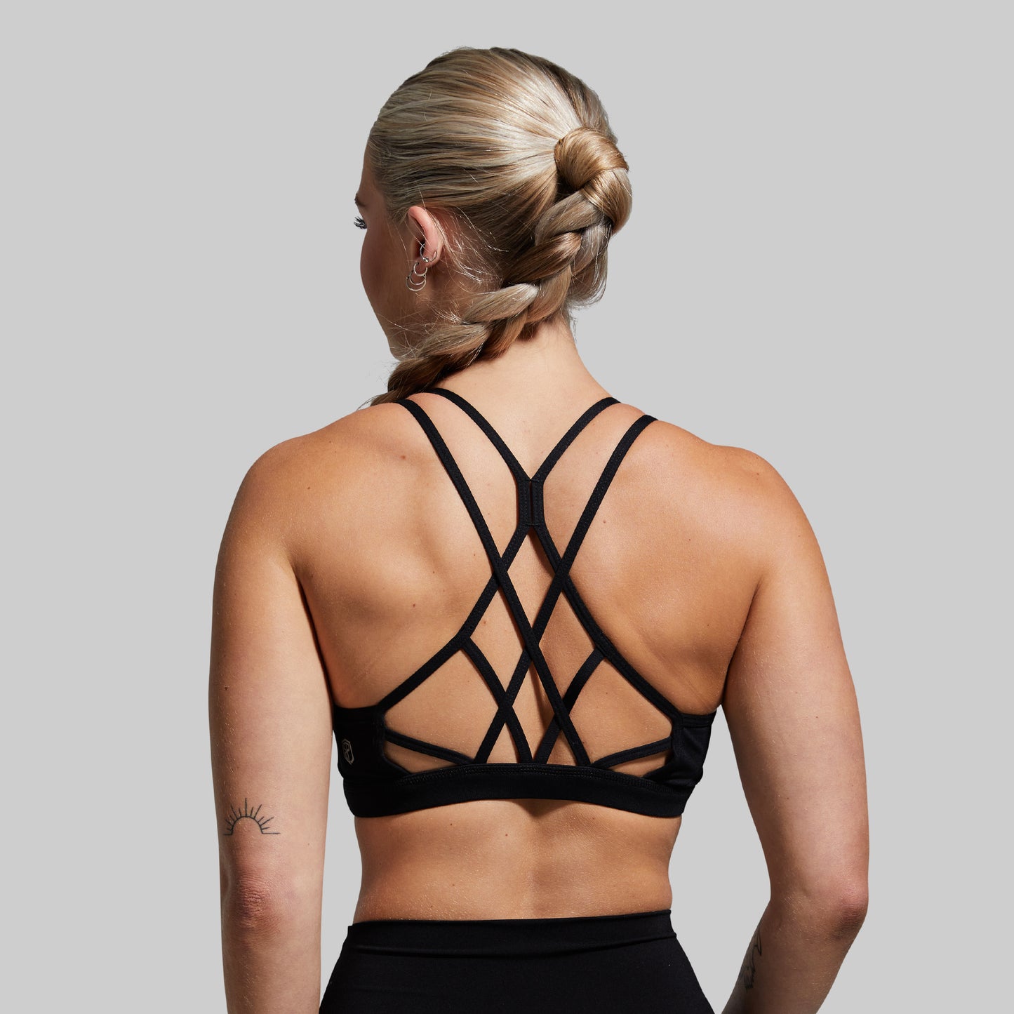 Person wearing a black strappy sports bra against a gray background