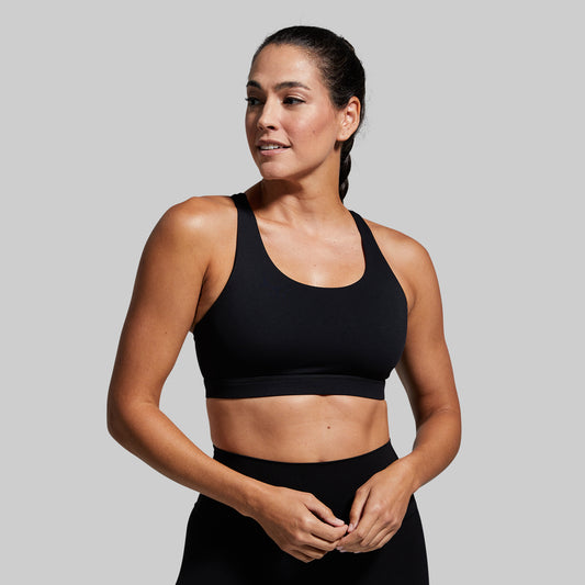 Woman wearing a black sports bra and leggings on a gray background