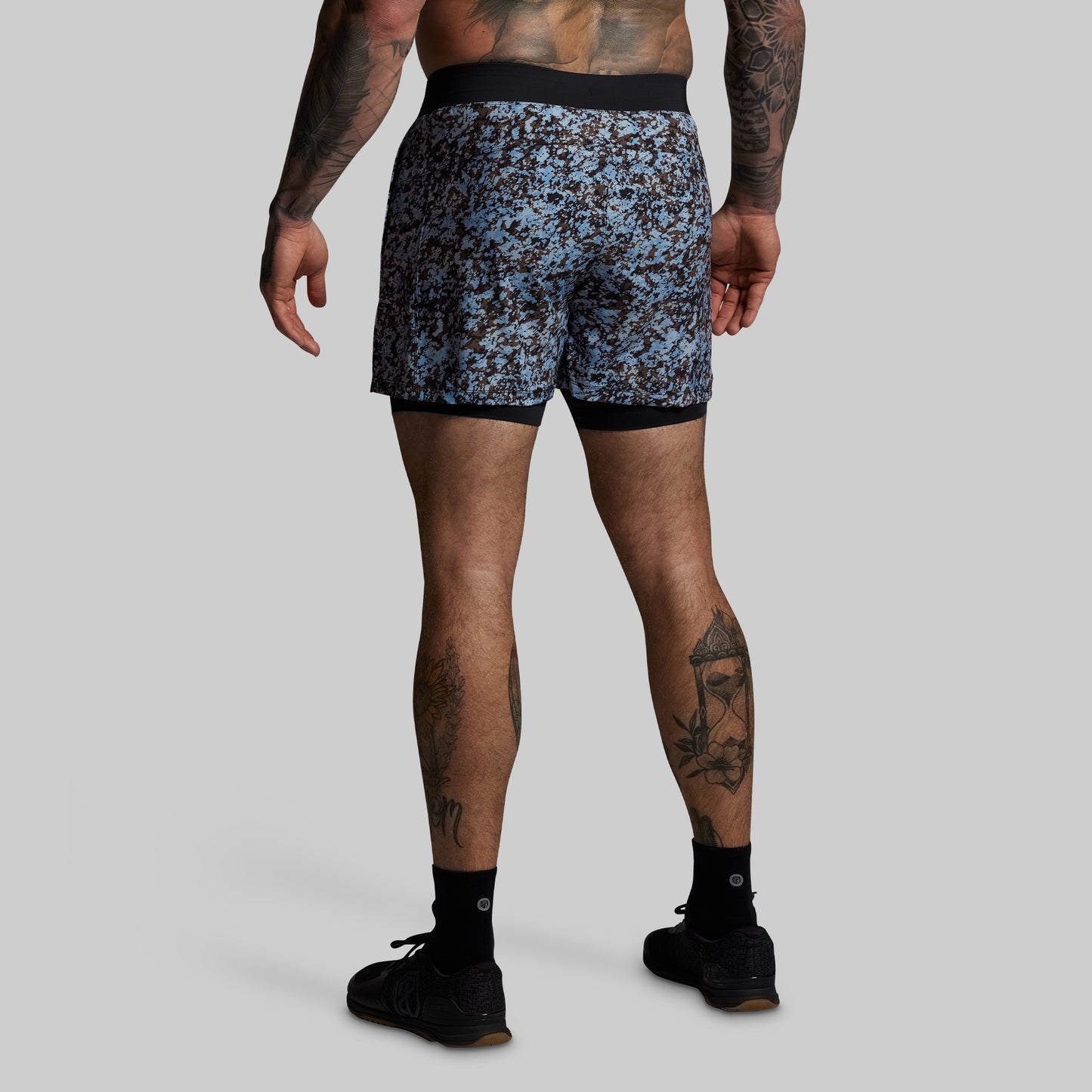 Person wearing blue camouflage shorts on a gray background