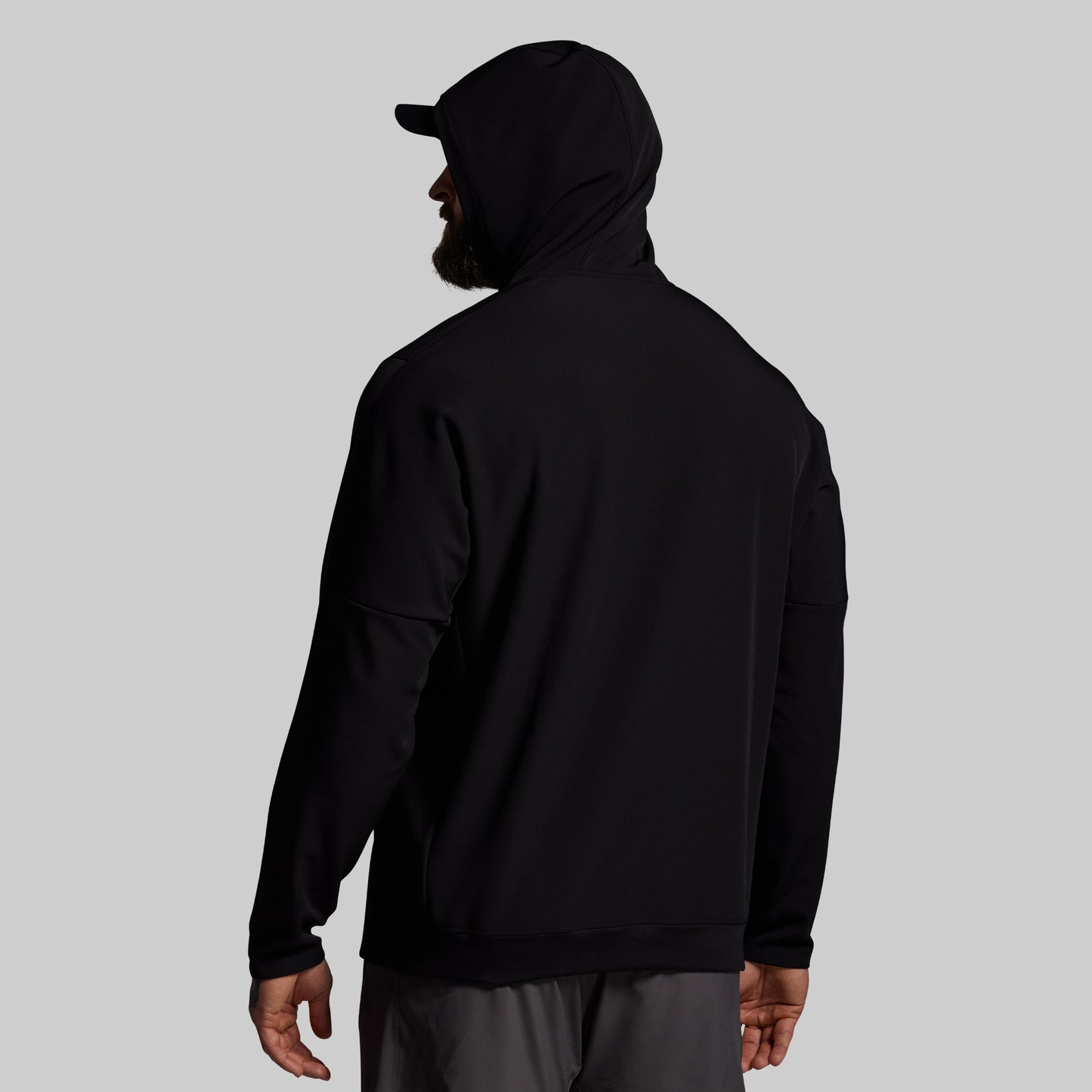 Person wearing a black hoodie and cap on a gray background