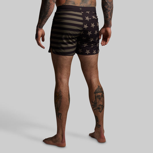 Person wearing black and green striped shorts with star pattern on a gray background