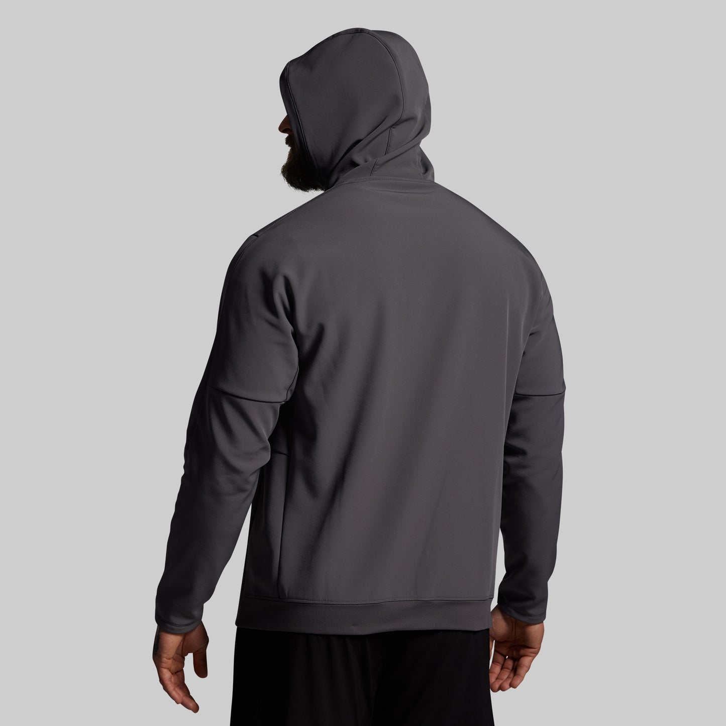 Person wearing a dark gray hoodie on a light gray background
