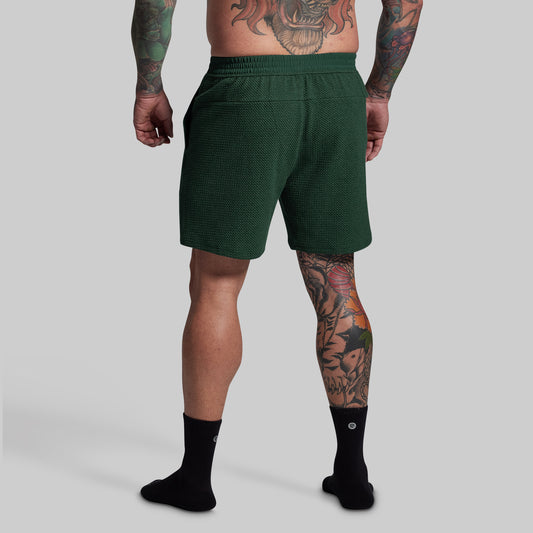 Person wearing green lounge shorts on a gray background