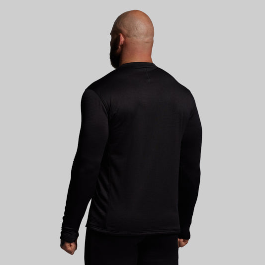 Person wearing a black long-sleeve shirt against a gray background
