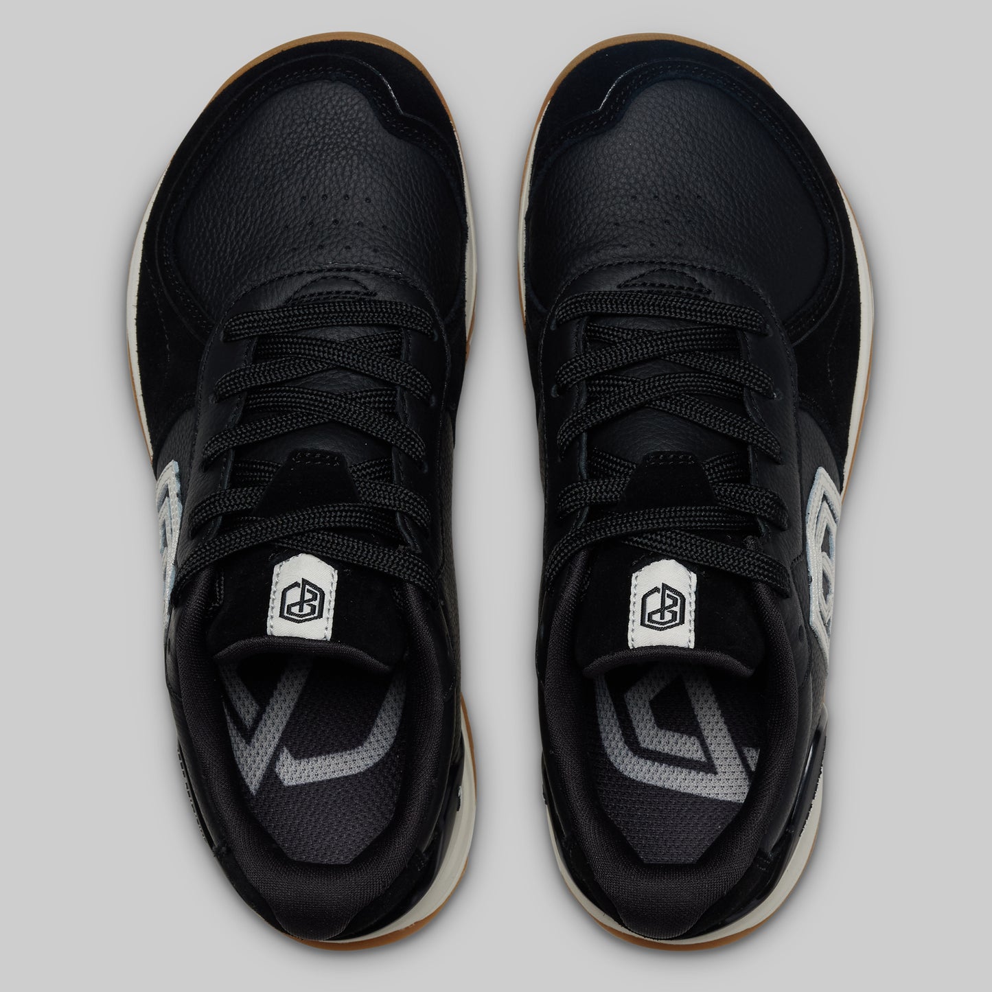 Black sneakers with a brand logo on a light gray background
