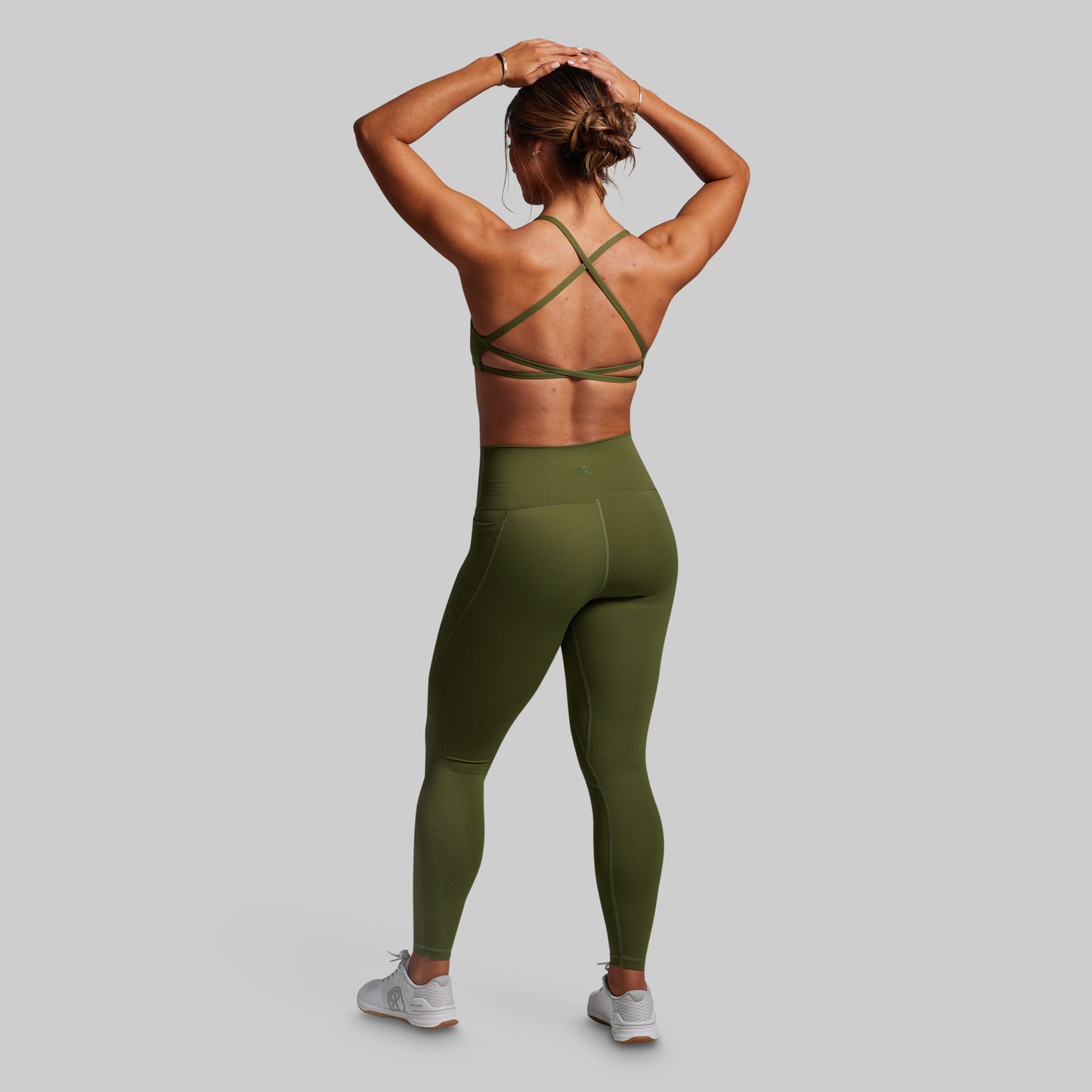 Person wearing a green sports bra and leggings set on a gray background