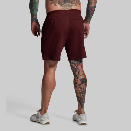 Person wearing maroon shorts on a plain background