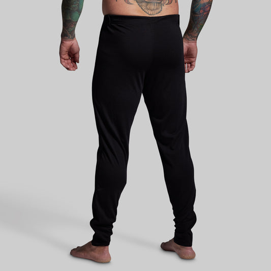 Person wearing black pants on a plain background