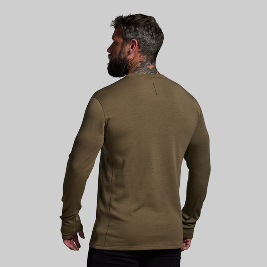 Man wearing a green long-sleeve shirt on a gray background