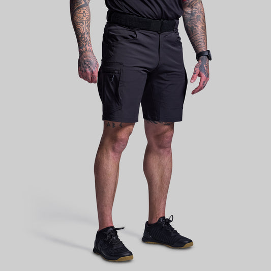 Person wearing black shorts and black shoes on a gray background