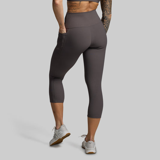 Woman wearing gray capri leggings on a gray background