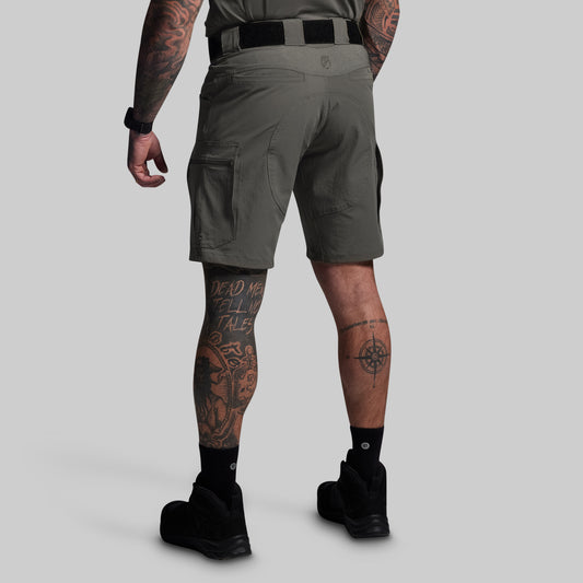 Person wearing green tactical shorts on a light gray background