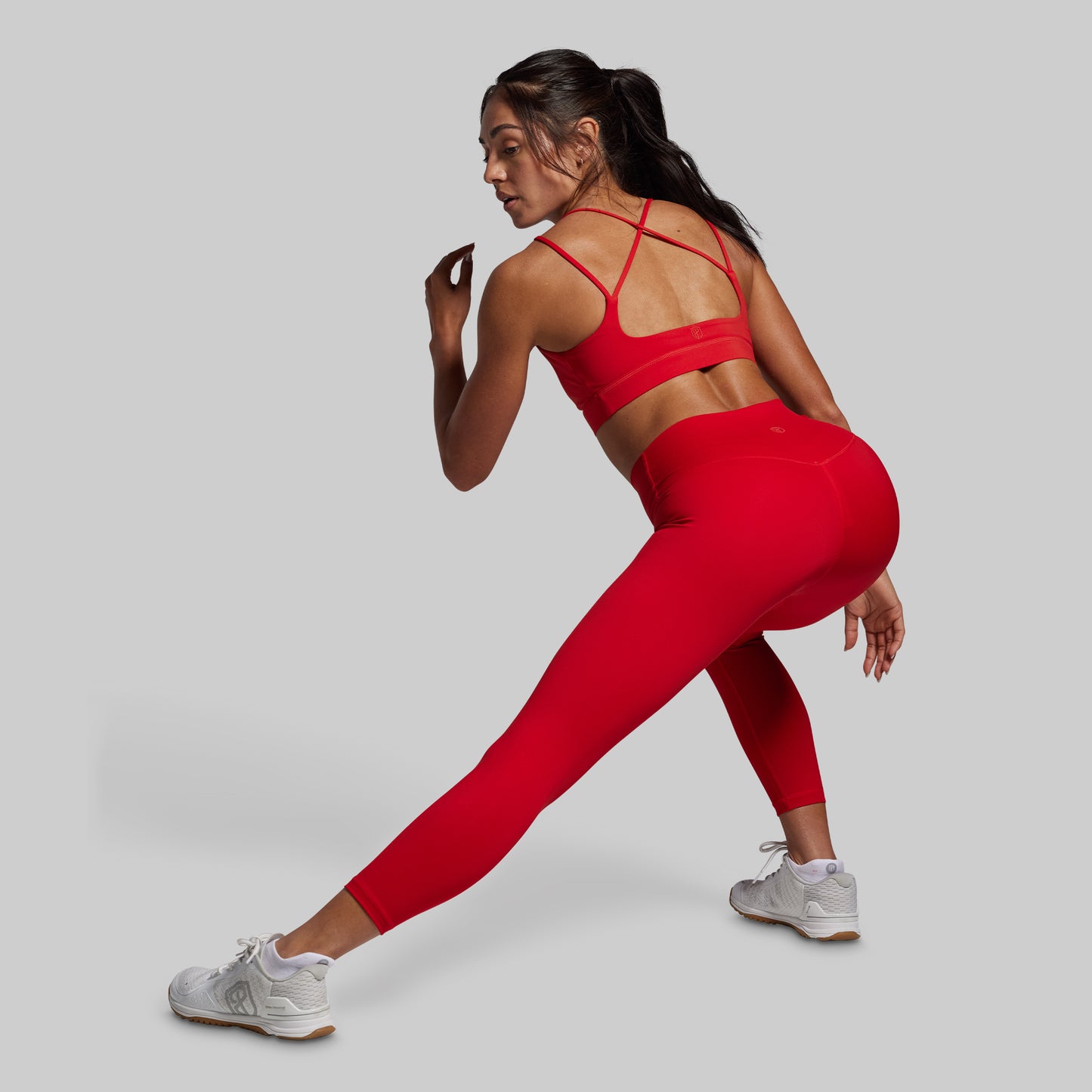 Woman in red athletic wear posing against a gray background