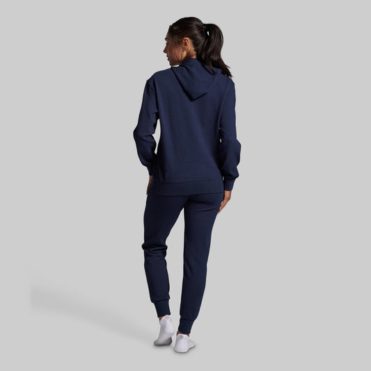 Person wearing a navy tracksuit on a light gray background
