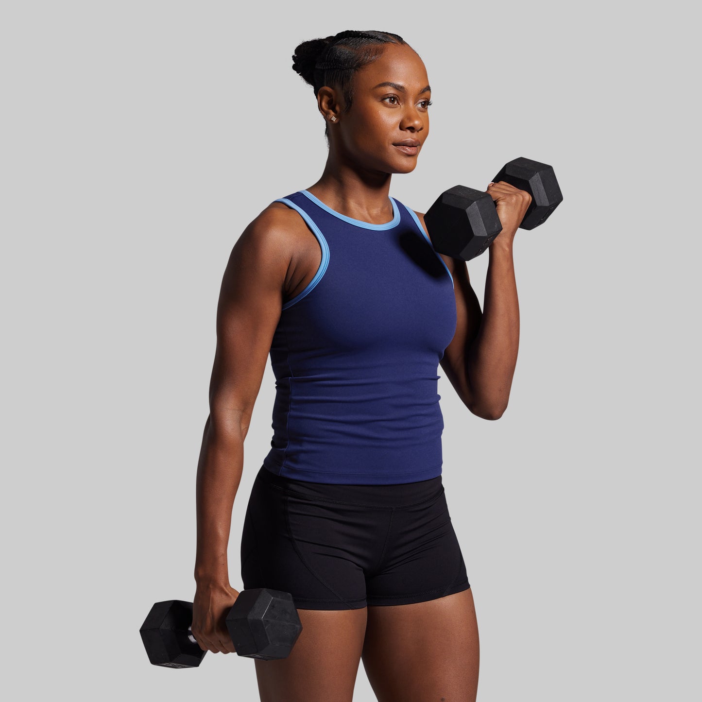 Woman holding two dumbbells against a gray background