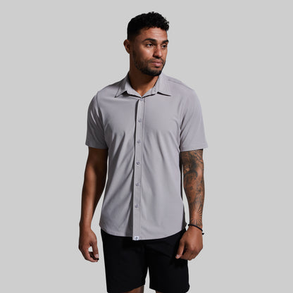 Man wearing a gray short-sleeve shirt against a plain background