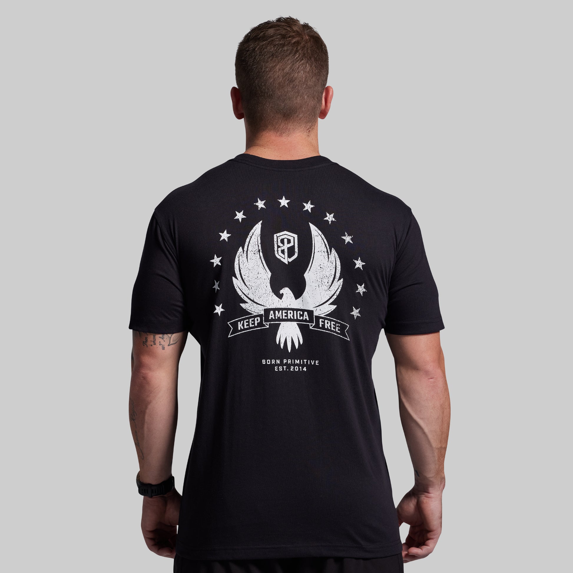 Man wearing a black t-shirt with a white graphic design on the back against a gray background