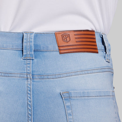 Close-up of light blue jeans with a brown leather patch on the back pocket.