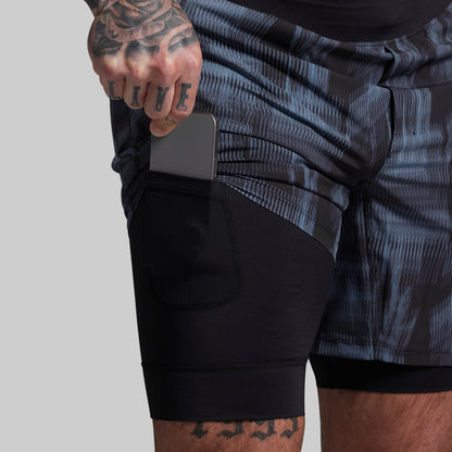 Person wearing a black and gray patterned athletic shorts with a plain background