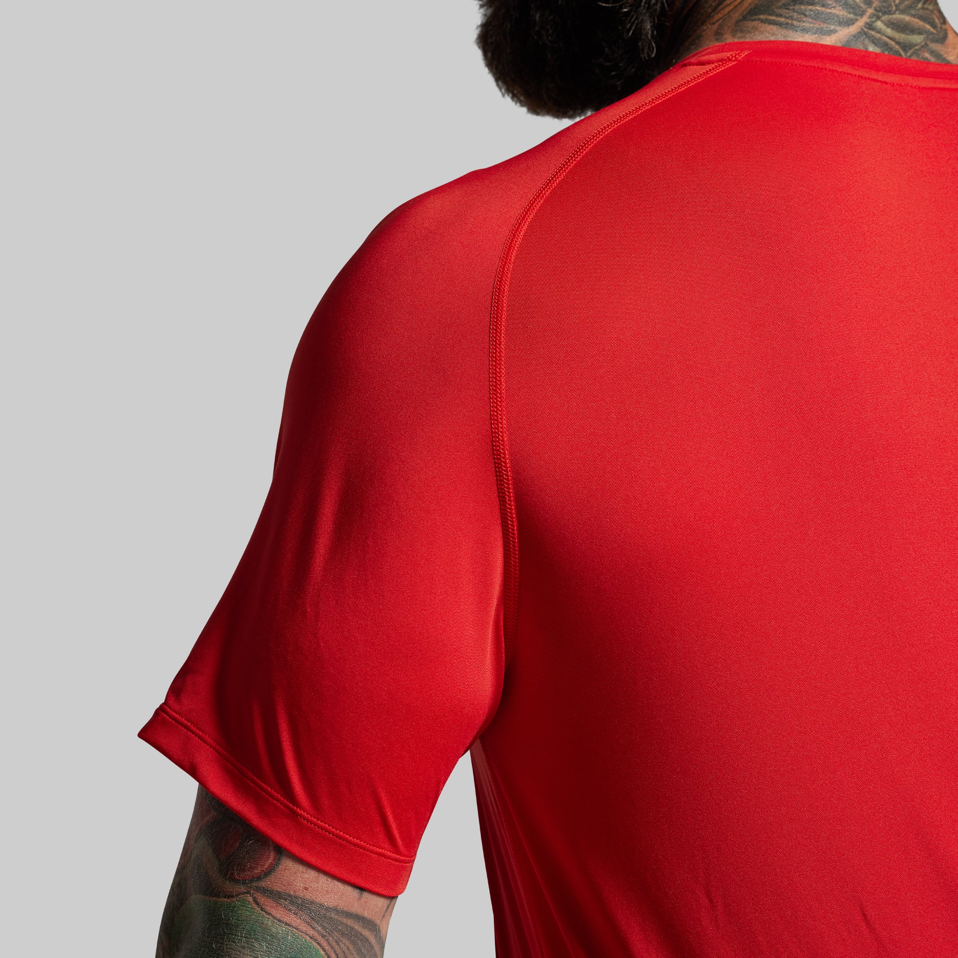 Red athletic shirt worn by a person on a gray background
