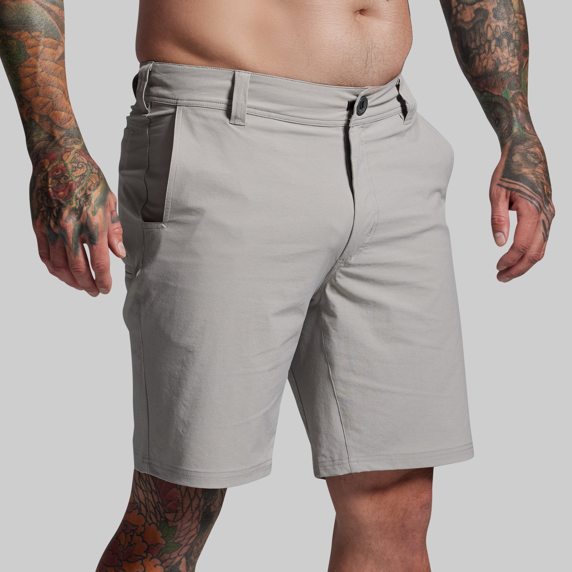 Gray shorts worn by a person with tattoos on a plain background