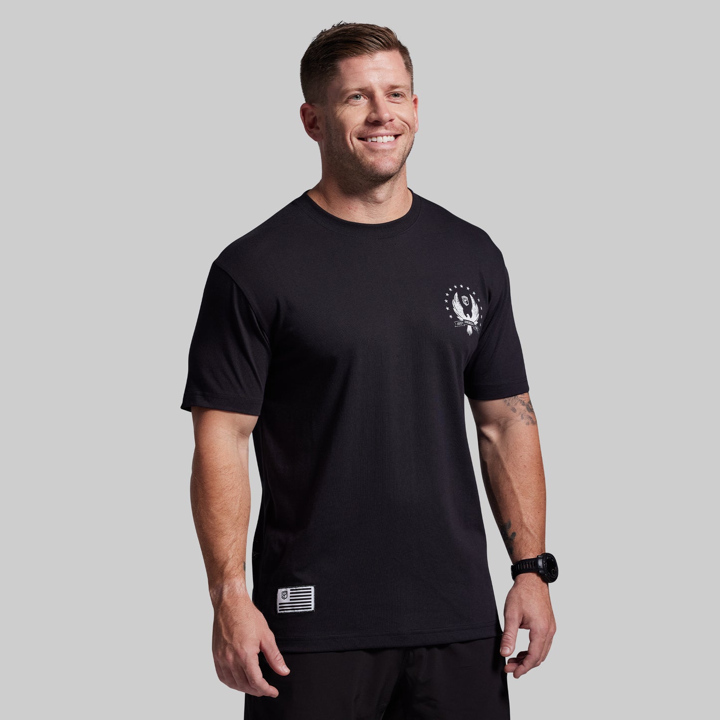 Man wearing a black t-shirt with a logo on a gray background