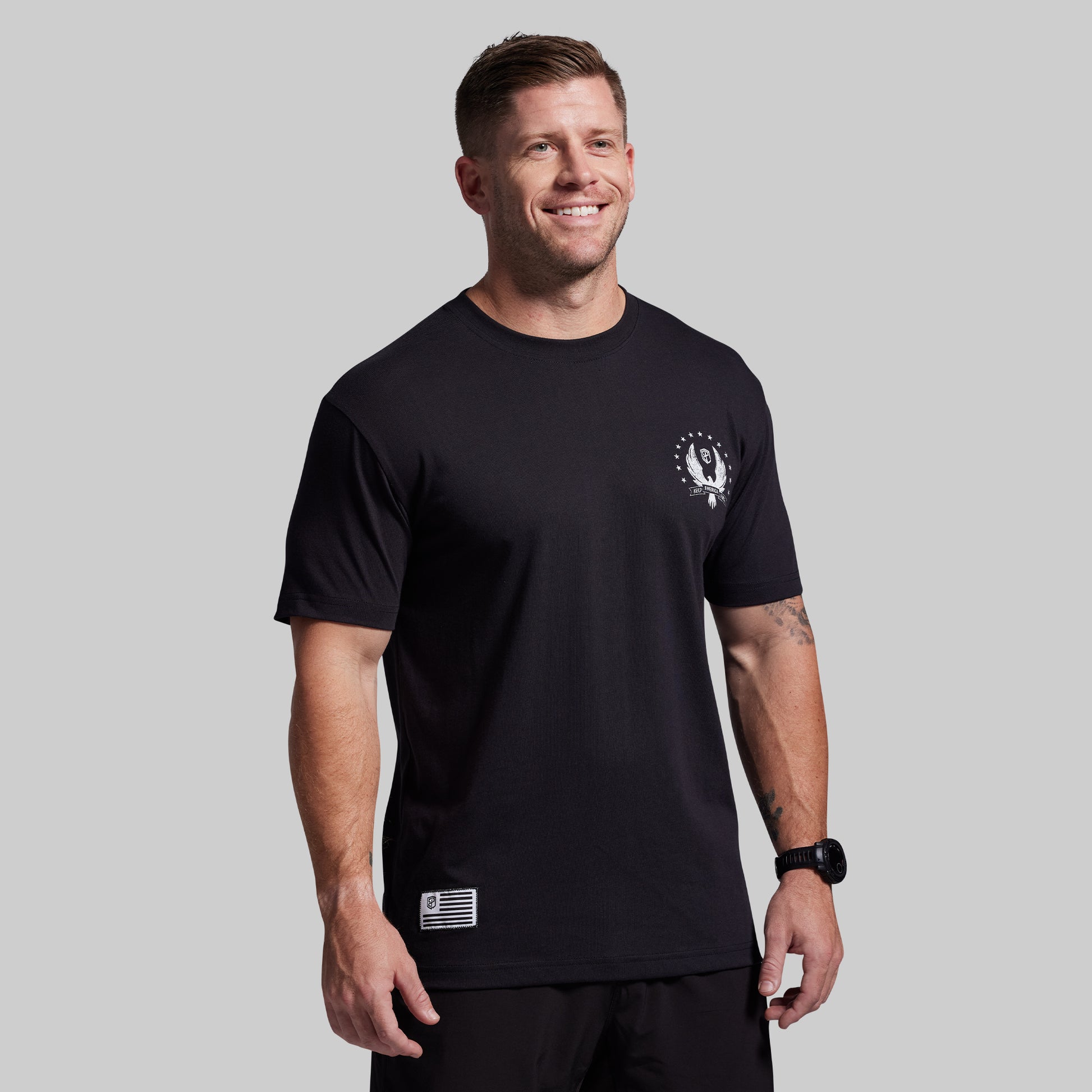 Man wearing a black t-shirt with a logo on a gray background