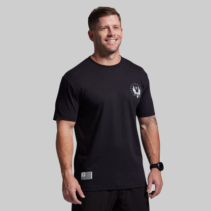 Man wearing a black t-shirt with a logo on a gray background
