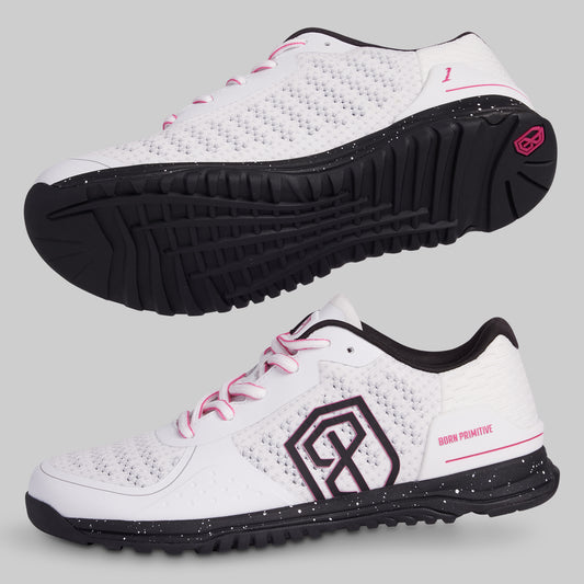 White athletic shoes with black soles and pink accents on a light gray background
