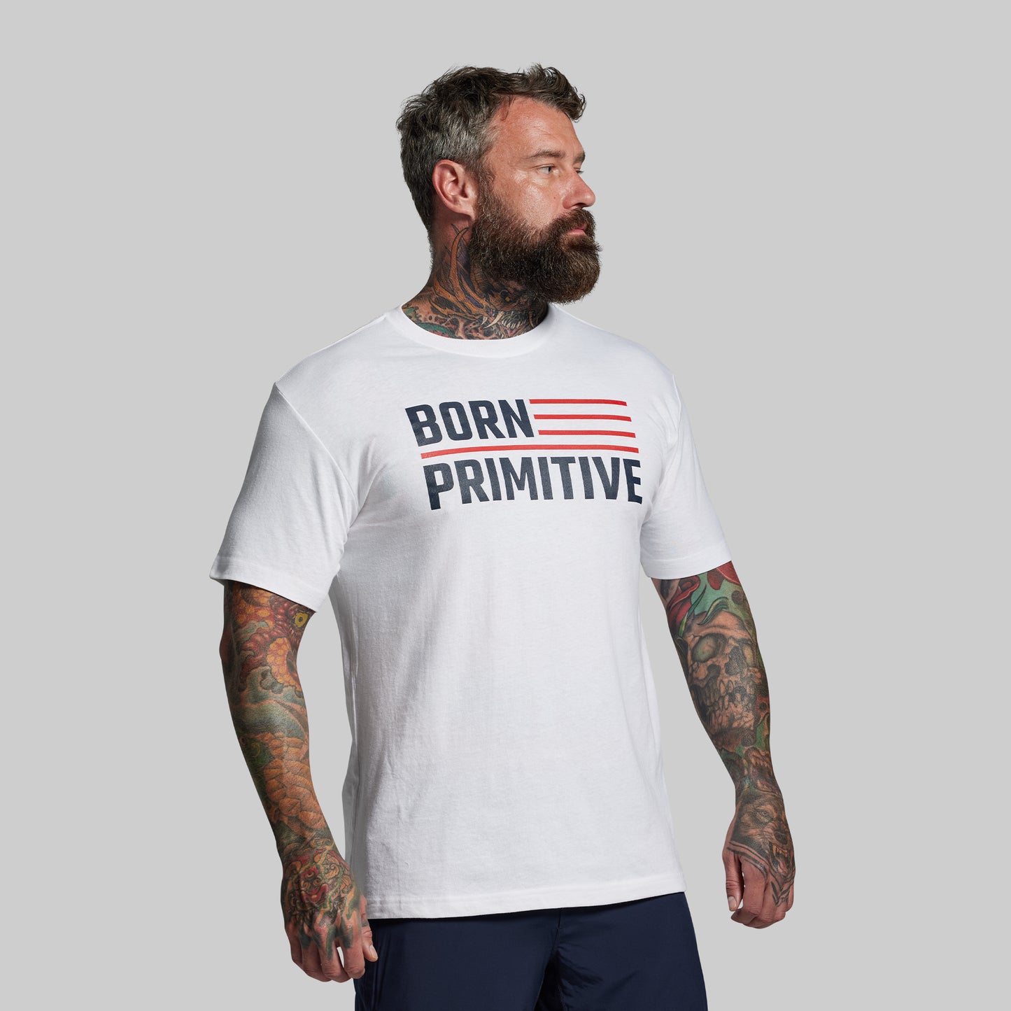 Man wearing a white t-shirt with 'Born Primitive' text on a gray background