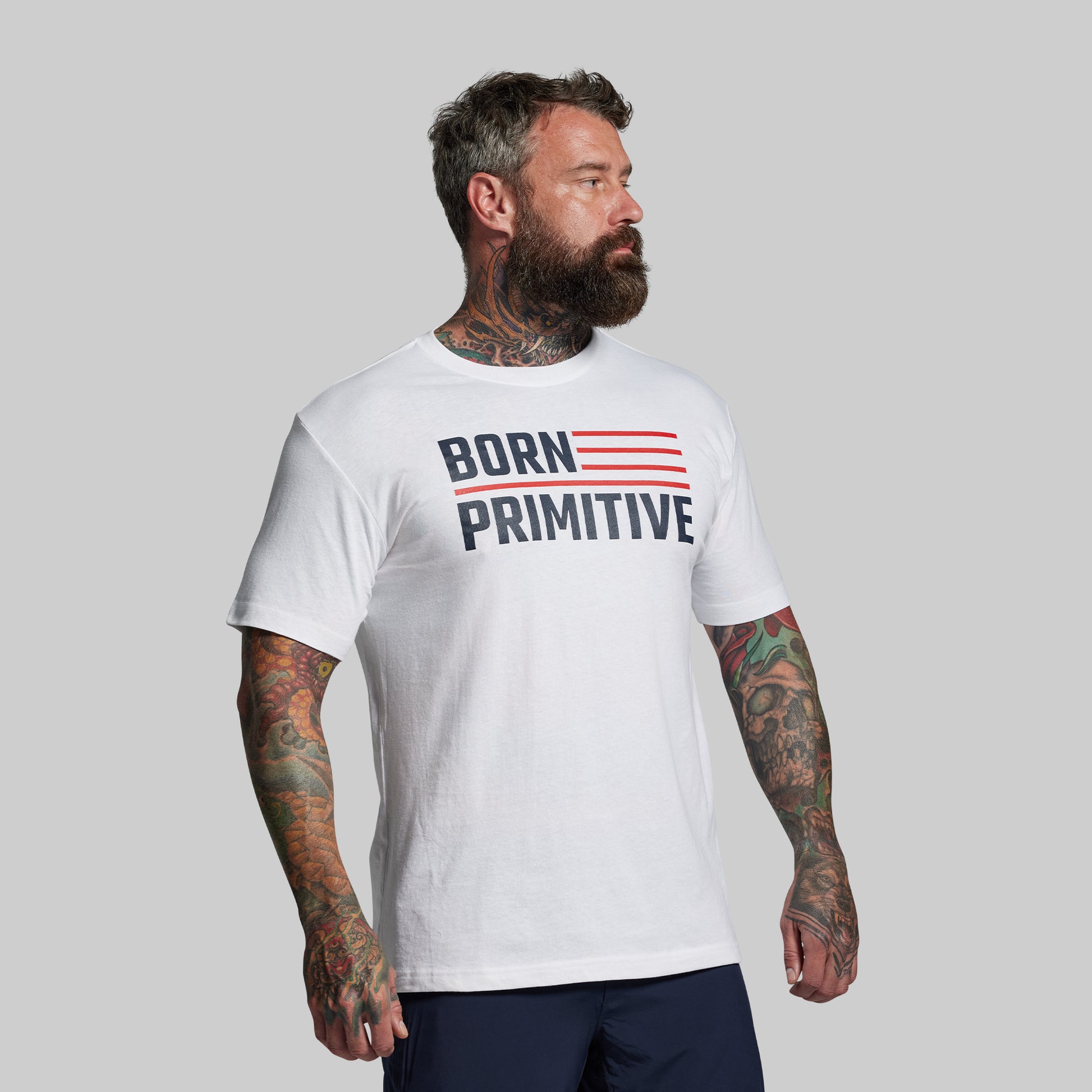 Man wearing a white t-shirt with 'Born Primitive' text on a gray background