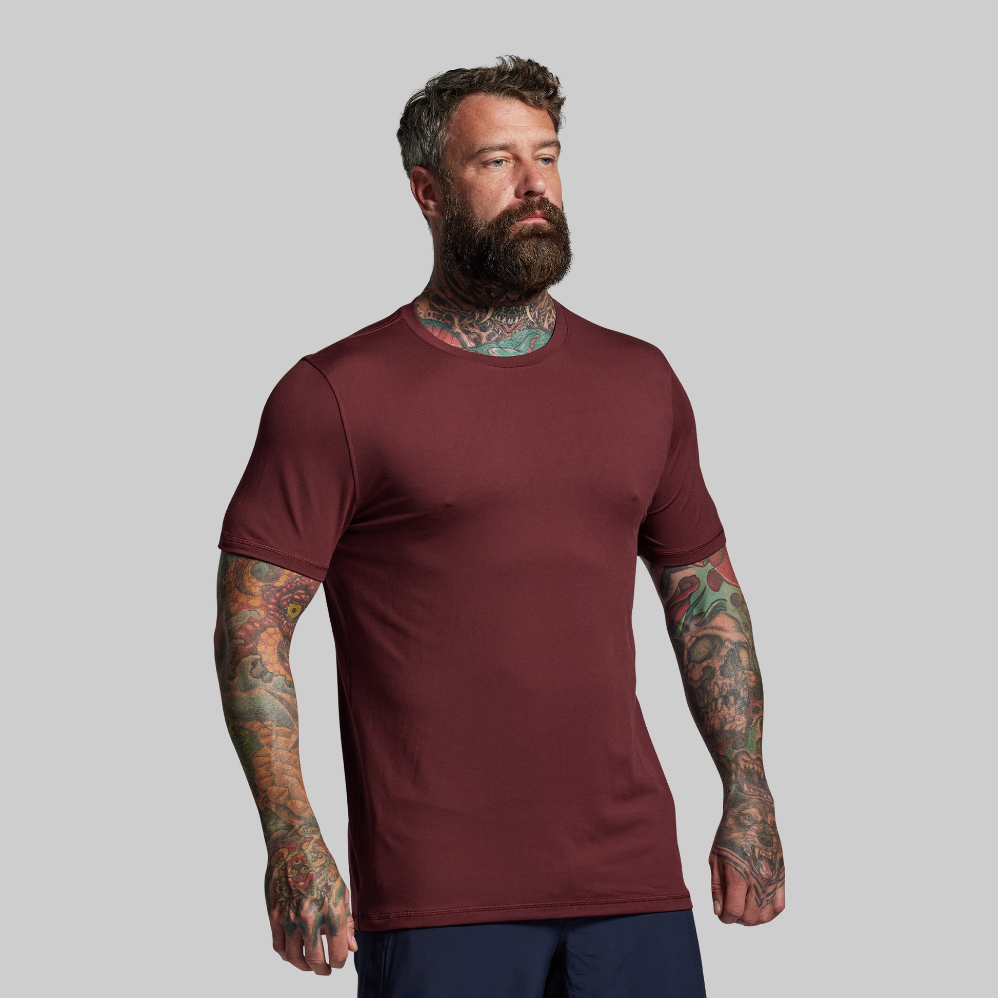 Man wearing a maroon t-shirt against a gray background