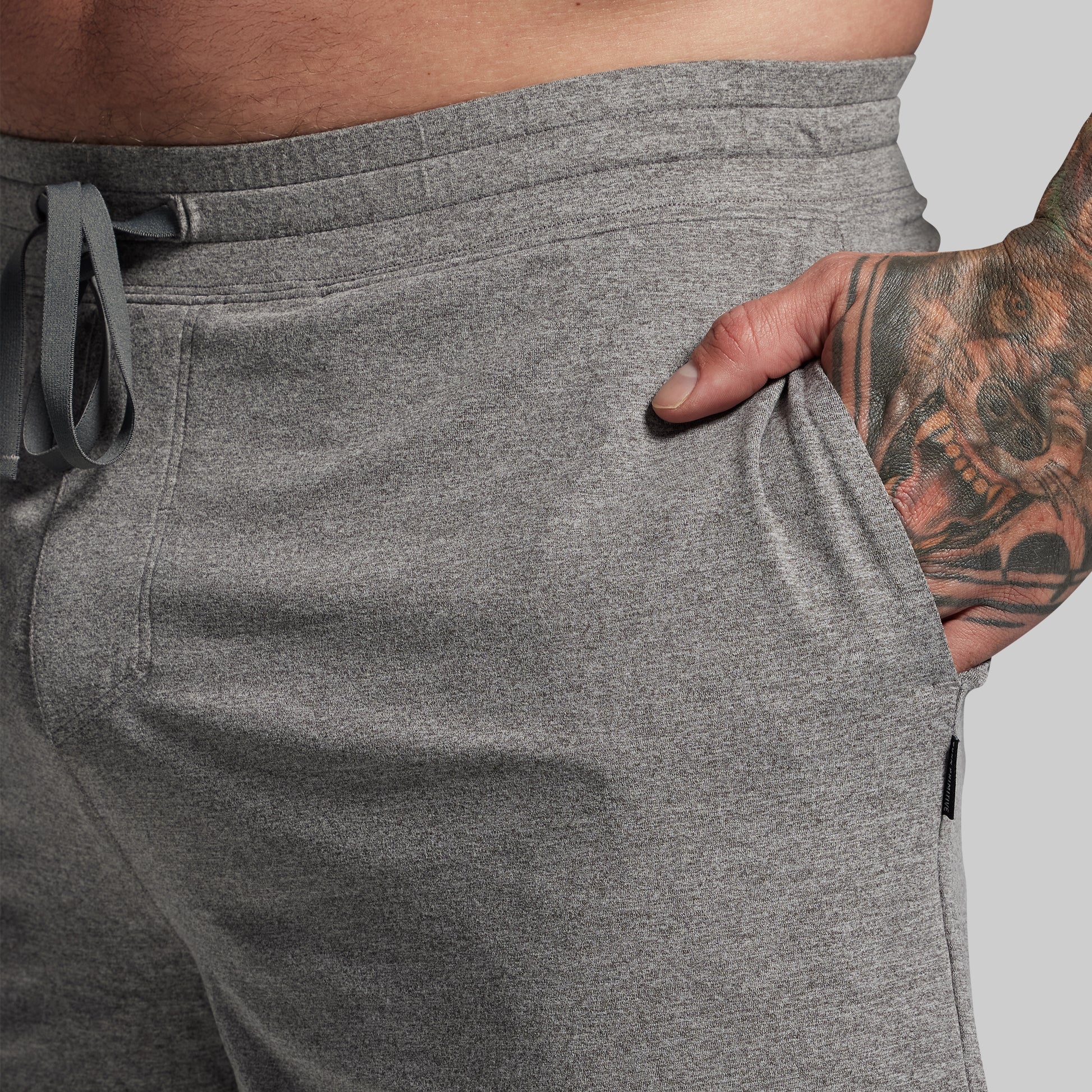Person wearing gray shorts with a tattooed hand in pocket.