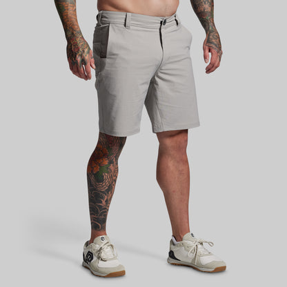 Person wearing light gray shorts on a plain background