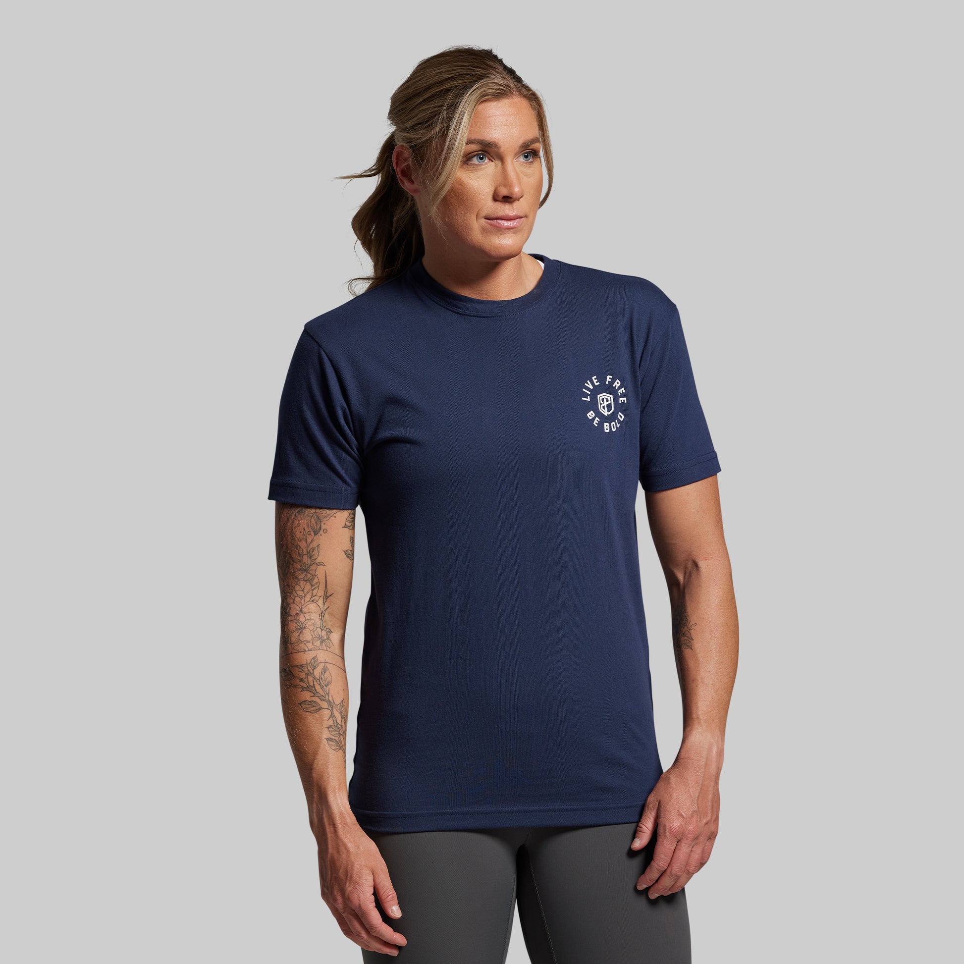 Person wearing a navy blue t-shirt with a logo on a gray background