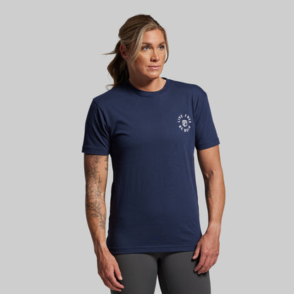 Person wearing a navy blue t-shirt with a logo on a gray background