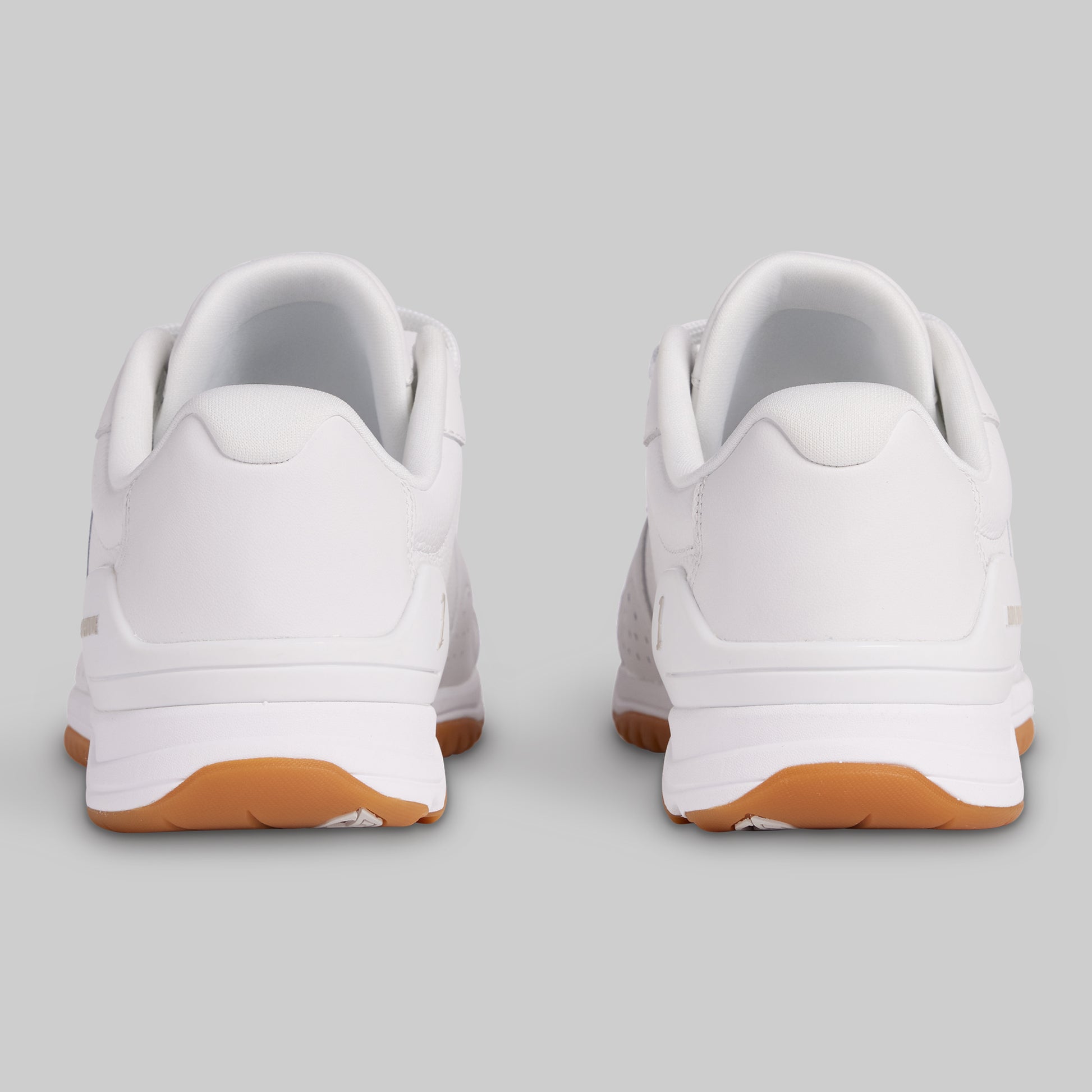 White sneakers with brown soles on a light gray background
